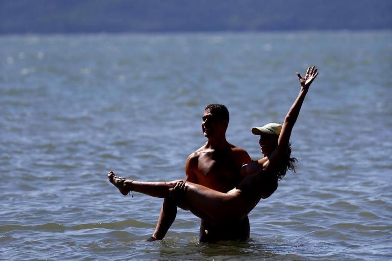 Homem Pega Mulher no Colo em uma Praia Naturalista 